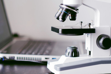 Microscope and laptop on table. Chemical research, student work in natural Sciences