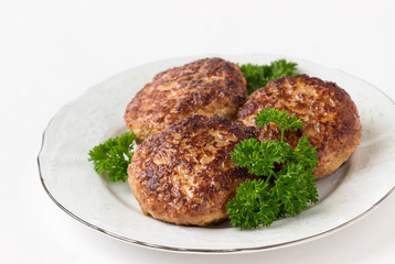 Homemade cutlets with parsley on a white plate and white background.