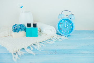 Bathroom accessories. Shower gel, shampoo, soap  and blue alarm clock on blue wooden table for the bath.