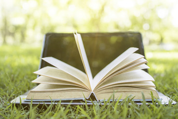book and laptop in park, knowledge and education concept