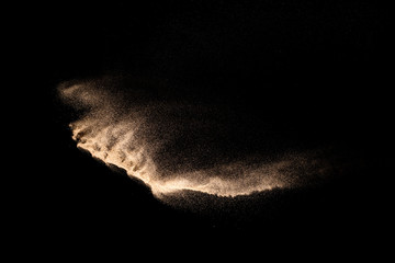 Golden sand explosion isolated on black background. Abstract sand cloud. Golden colored sand splash...