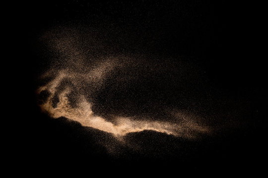Golden sand explosion isolated on black background. Abstract sand cloud. Golden colored sand splash against dark background. Yellow sand fly wave in the air.