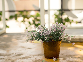 White and purple plastic flowers in vase decorative table outside home. Home design.