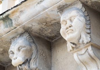 Closeup view of mascarons with funny faces under the balcony of a baroque palace in the province of Syracuse, Sicily