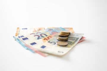 Euro banknoted and a stack of euro coins isolated on white background