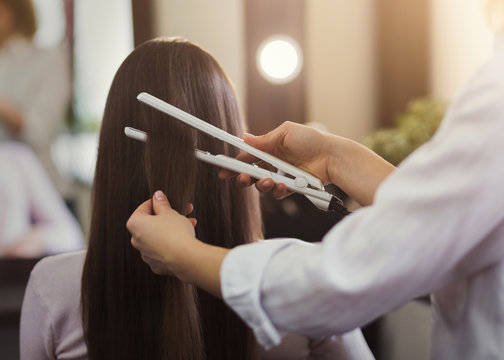 Hairdresser straightening long brown hair