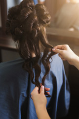 Hairdresser making curly hair to client