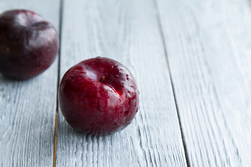 two red plums on a grey wooden background