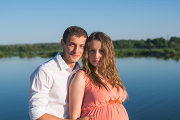 Young happy pregnant couple resting outdoors in summer