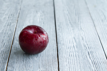 one wet red plum on a grey wooden background