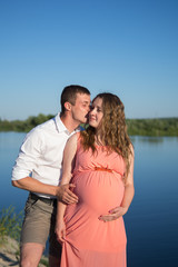 Young happy pregnant couple resting outdoors in summer