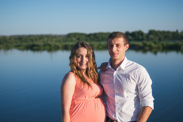 Young happy pregnant couple resting outdoors in summer