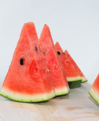 Sliced red watermelon on a wooden cutting board. Isolated.