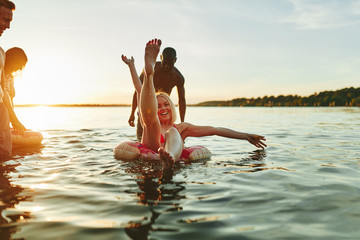 Smiling friends having fun together in a lake at sunset