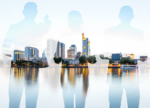 Silhouettes of business people standing back on the modern cityscape background with skyscrapers in Frankfurt. Double exposure image technic