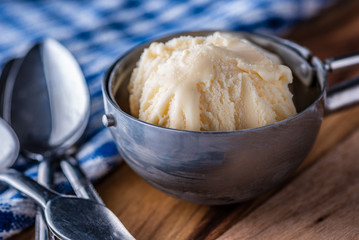 A scoop of vanilla ice cream on a wooden board and blue and white dish towel.

