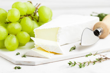 Brie cheese, Camembert with green grapes, thyme on Board, delicious product