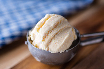 A scoop of vanilla ice cream on a wooden board and blue and white dish towel.
