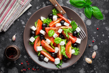 Salad with tomatoes, feta, olives and Basil, serving on a dark background
