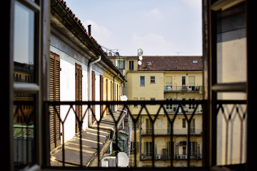 Fototapeta na wymiar View of a typical Italian interior courtyard from the highest floor of the building through a window full day. Photograph taken in Torino, Italy.