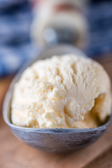 A single scoop of vanilla ice cream on a wooden board
