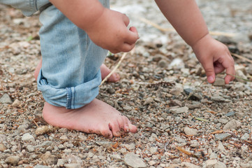 closeup of feet of child playing on the beach with stone