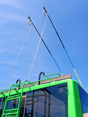 green trolleybus metal bars with stairs on blue sky with white clouds, power outage, modern urban...