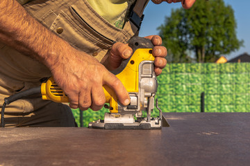 A carpenter cuts a kitchen worktop with a jigsaw. Concept: construction site or craft