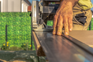 A carpenter cuts a kitchen worktop with a circular saw. He uses an attachment rail for a straight cut. Concept: construction site or craft