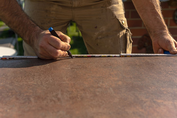 A carpenter distinguishes the dimensions for the cutting of the worktop. Concept: construction site or craft