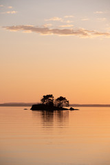 Small island in the lake with land in the background