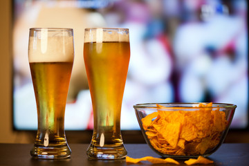 beer glasses and chips in front of tv - watching world cup football at home - soccer supporters