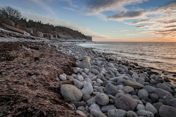 Soft stones on the beach with boats and fishing huts in the background