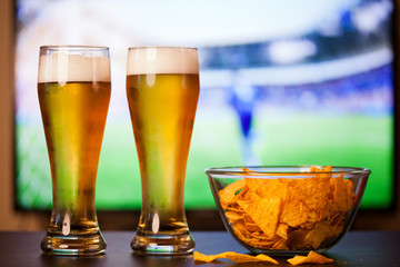 beer glasses and chips in front of tv - watching world cup football at home - soccer supporters