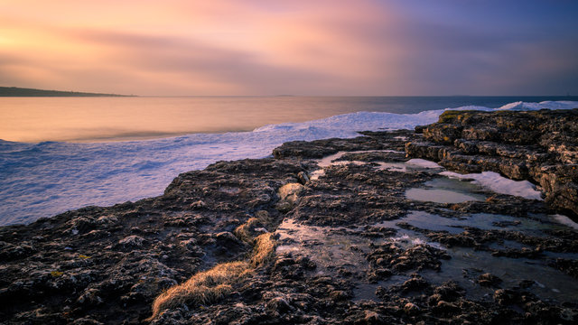 Long exposure photo at sea with sea cliffs and snow in the foreground