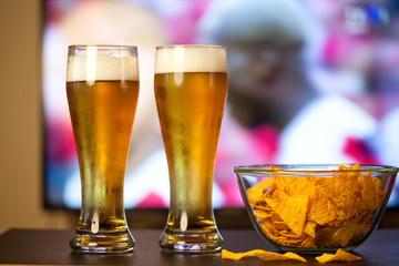 beer glasses and chips in front of tv - watching world cup football at home - soccer supporters