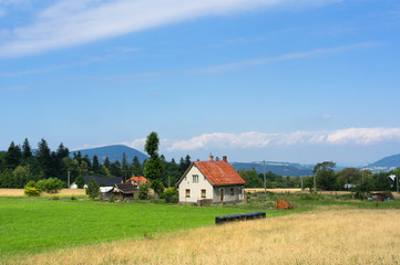 Fototapeta na wymiar Cottage in the countryside. Authentic village in Czech Republic. Beskid mountains in the distance. 