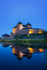 Beautiful view of lit 13th century Häme Castle and its reflections on lake Vanajavesi in Hämeenlinna, Finland, at night.