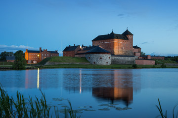 Beautiful view of lit 13th century Häme Castle and its reflections on lake Vanajavesi in Hämeenlinna, Finland, in the evening.