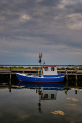 Fototapeta na wymiar Blue and whithe fishing boat with reflections in the water