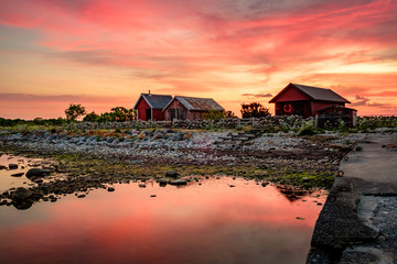 Red fishing huts during sunrise and stones on the beach