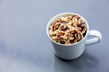 White cup full of walnuts on grey background. Above view