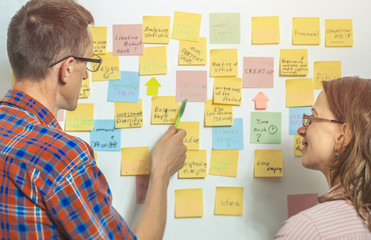 Business people discuss and plan creative work, making notes on paper stickers. A young man and a...