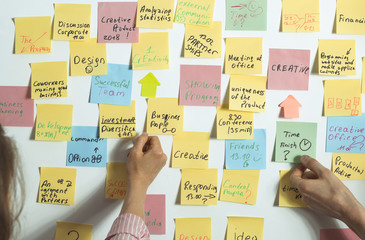 Business people discuss and plan creative work, making notes on paper stickers. A young man and a...