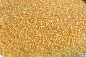 On a white glass plate in the light of the sun, poured natural pear gelatin for the preparation of fruit jelly in the form of loose yellow crutches