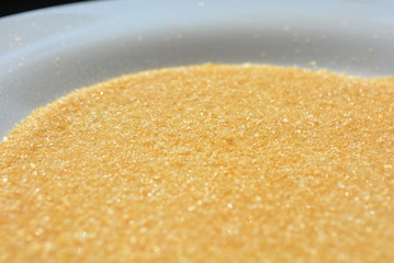 On a white glass plate in the light of the sun, poured natural pear gelatin for the preparation of fruit jelly in the form of loose yellow crutches