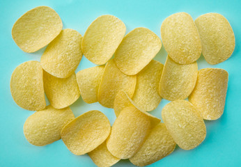 Salted yellow chips on blue background. Above view