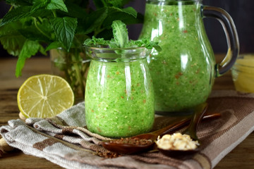Green smoothie in a glass jar and jug topped with mint