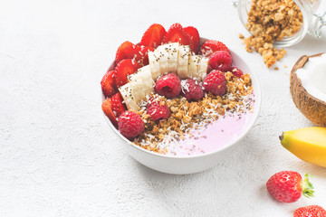 Pink smoothie in bowl with banana, strawberry and raspberry