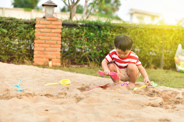 Asian boy playing with sand in playground
